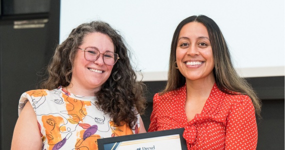 Administrator standing on stage with a student accepting a framed award